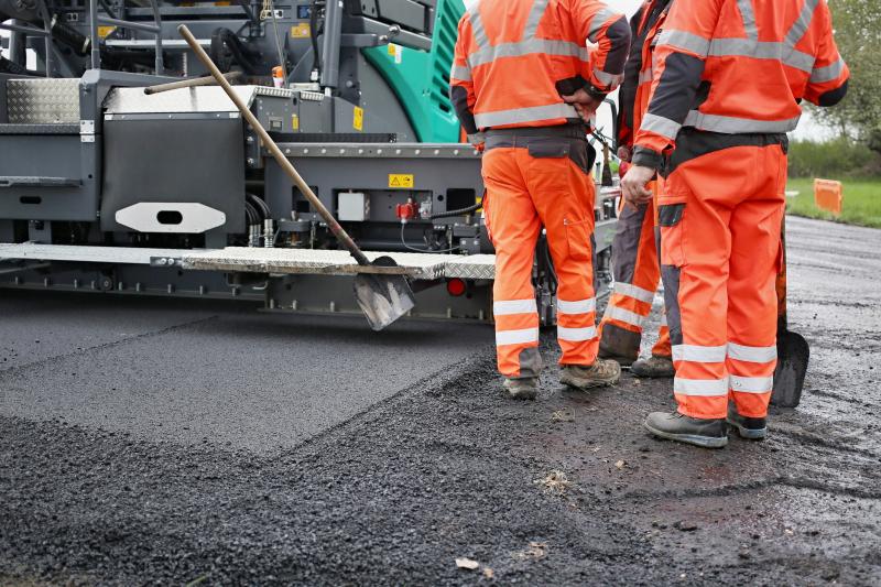 Photograph of Road repair. Tractor, roller, construction workers on road repair site.