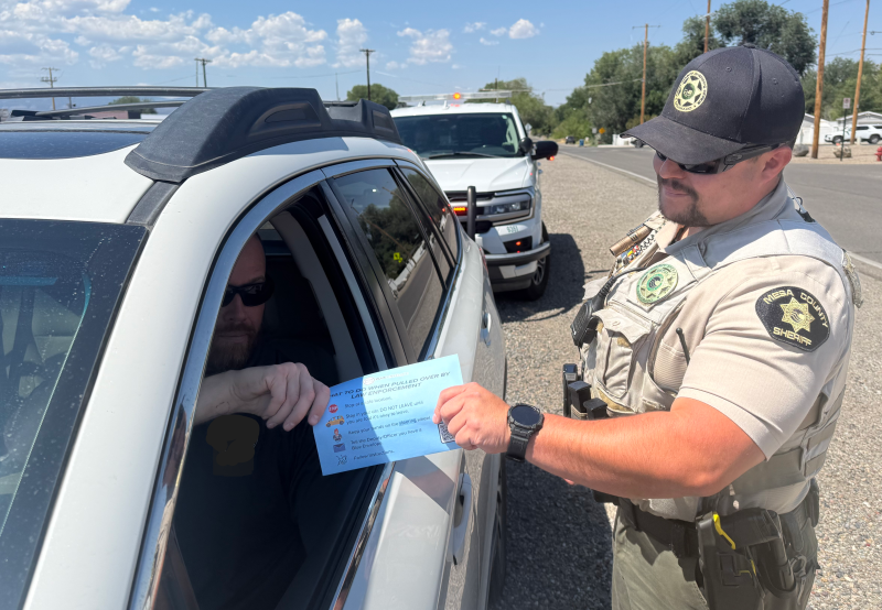 Driver handing a blue envelope to deputy on a traffic stop