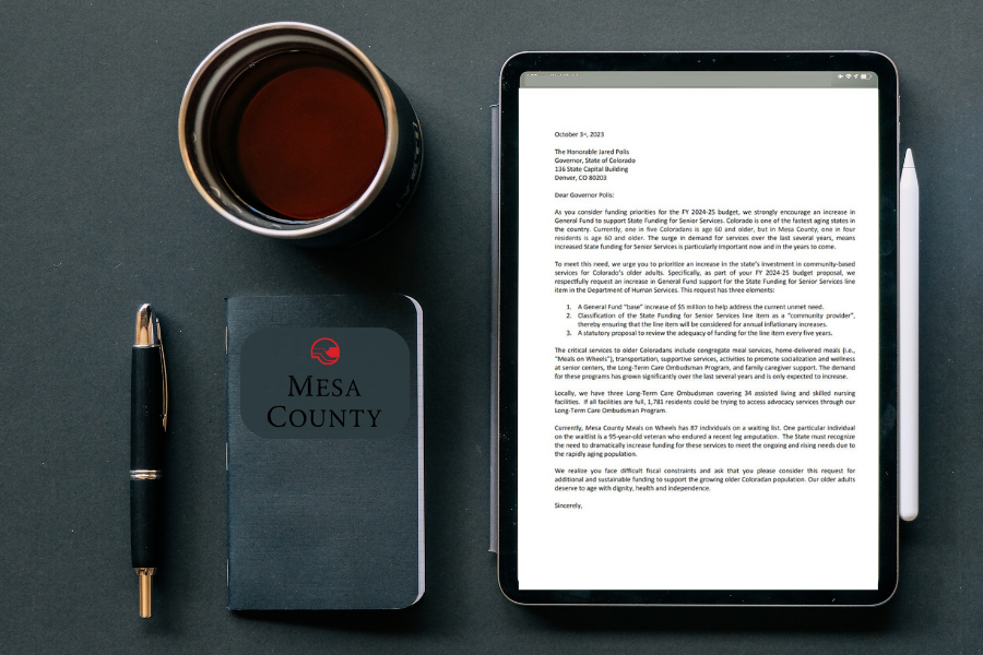 Coffee, pen, black journal, and iPad with letter on screen. 