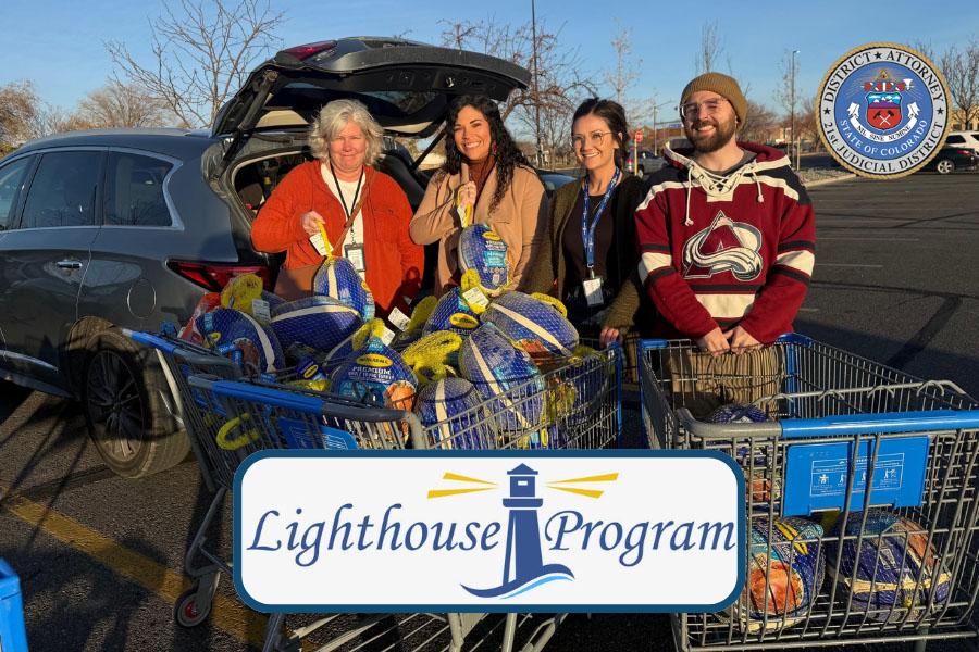 Four people standing with two shopping carts full of frozen turkeys with text reading Lighthouse Program. 