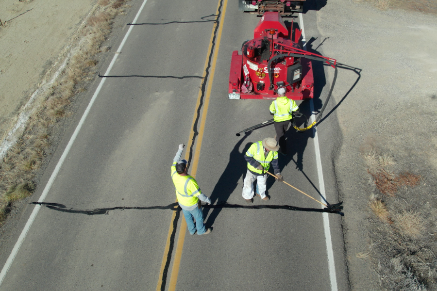  An aerial view shows a Mesa County road crew using specialized equipment to seal cracks on a rural road. 
