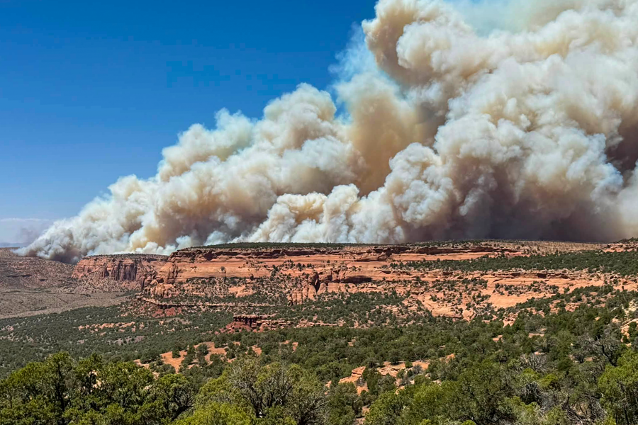 Smoke rises from the Snyder Fire from burning vegetation in rugged terrain near the Utah-Colorado border.