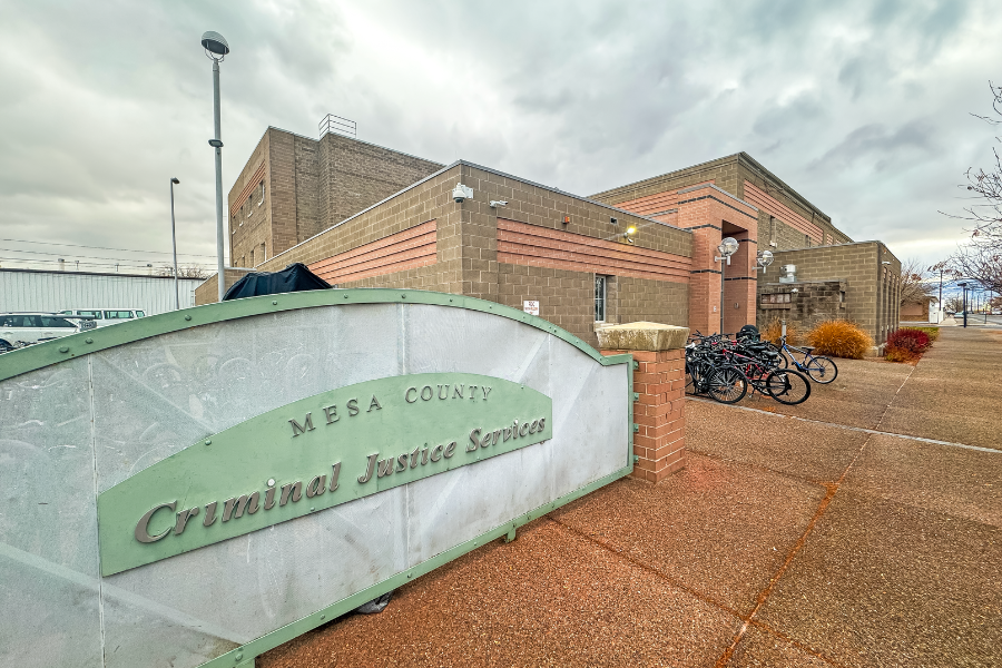 The Mesa County Criminal Justice Services building is shown from the sidewalk, with the facility entrance, bicycles and a sign identifying the department.